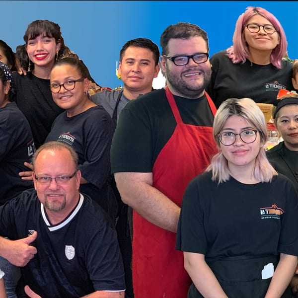Smiling La Tiendita Mexican Restaurant staff members, some wearing branded shirts and aprons, pose together.