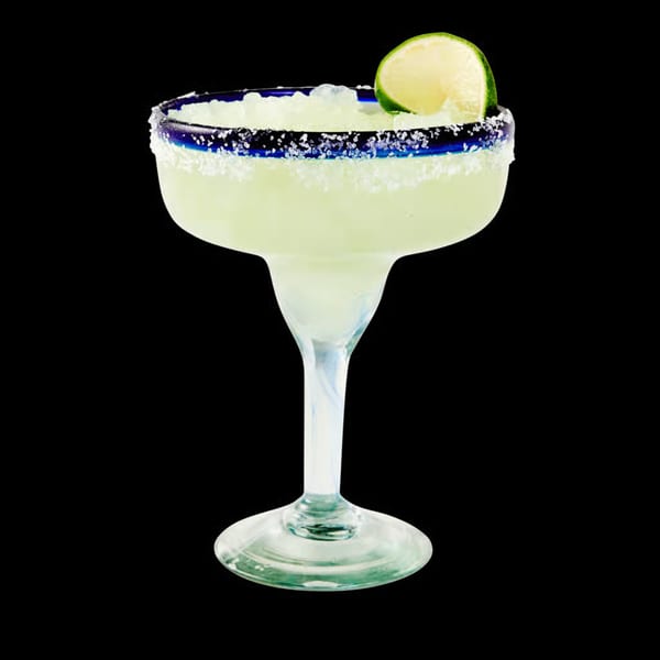 A La Tiendita margarita in a salt-rimmed glass with a lime wedge, against a black background.