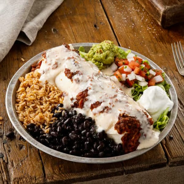 A La Tiendita Mexican Restaurant burrito covered in white sauce, with rice, black beans, guacamole, and pico de gallo.