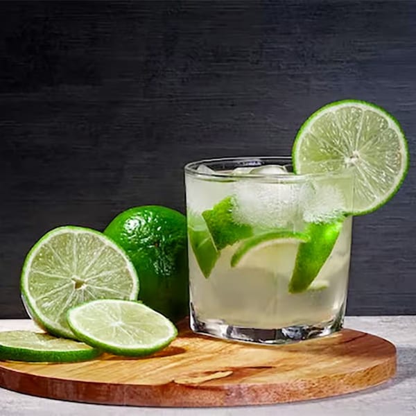 A refreshing lime drink with ice and lime slices on a wooden board at La Tiendita.