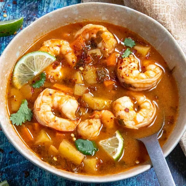 A bowl of La Tiendita's Mexican shrimp soup with lime, cilantro, and vegetables.